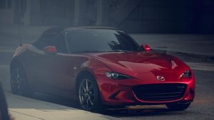 Red 2019 Mazda MX-5 Miata with a black convertible top parked next to a curb. | Mazda Dealer in Ellisville, MO
