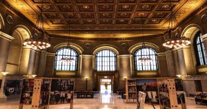 The inside of St Louis Public Library  with high ceilings, chandeliers, high arch windows, and an art display below. | Ellisville, MO