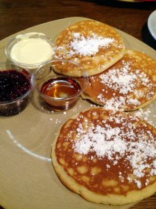 3 pancakes with powdered sugar on top on a plate.