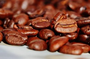 Close-up view of many coffee beans on a white counter. 