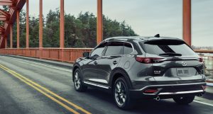 a charcoal 2020 Mazda CX-9 being driven across a bridge with trees in the background. | Mazda dealer in Ellisville, MO