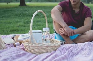 Close view of a man sitting on a blanket with a picnic basket at a park. | Ellisville, MO