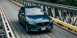 A darker turquoise 2020 Mazda CX-5 being driven across a bridge. | Mazda Dealer in Ellisville, MO