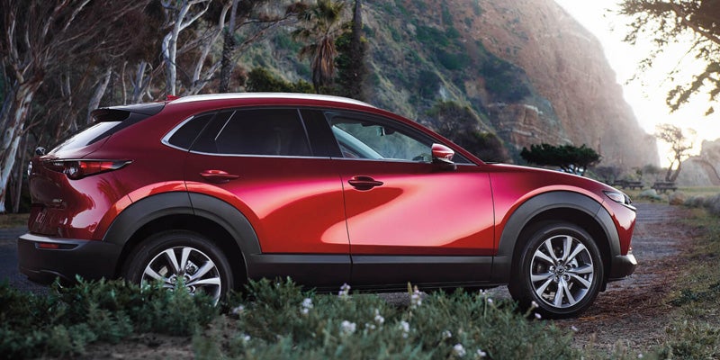 A red Mazda CX-30, a compact SUV, parked in an outdoor setting showcasing its sleek design and modern features.